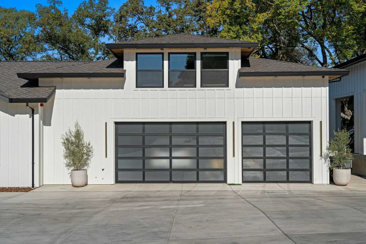 Modern white board-and-batten home with black-framed full-view glass garage doors