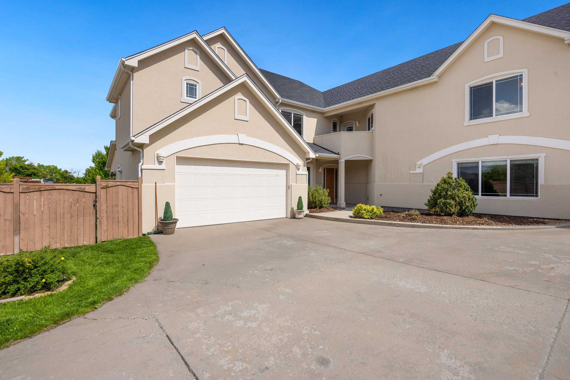 Two-story stucco home with an arched white raised-panel garage door and a wide driveway
